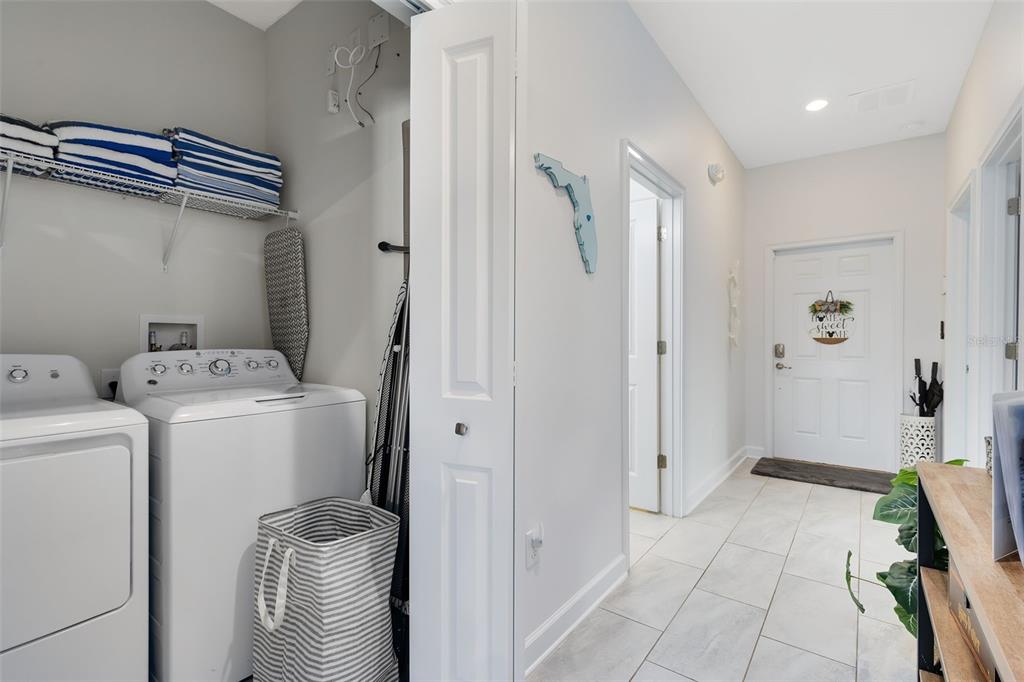 A laundry area with a washer and dryer sits beside a hallway leading to a door — 1575 SANDBAGGER DRIVE, DAVENPORT, FL