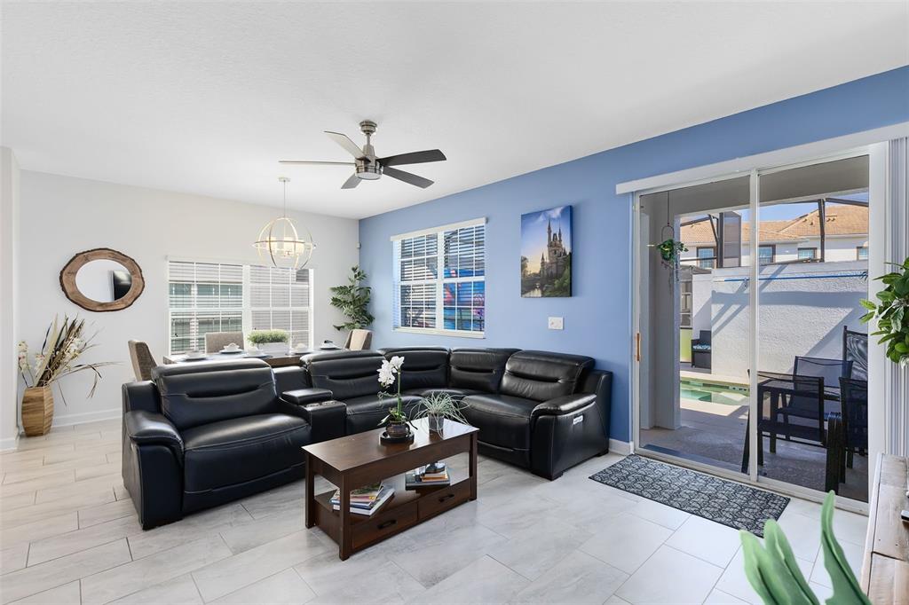 A living room with a black sectional sofa, wood coffee table, and blue accent wall — 1575 SANDBAGGER DRIVE, DAVENPORT, FL