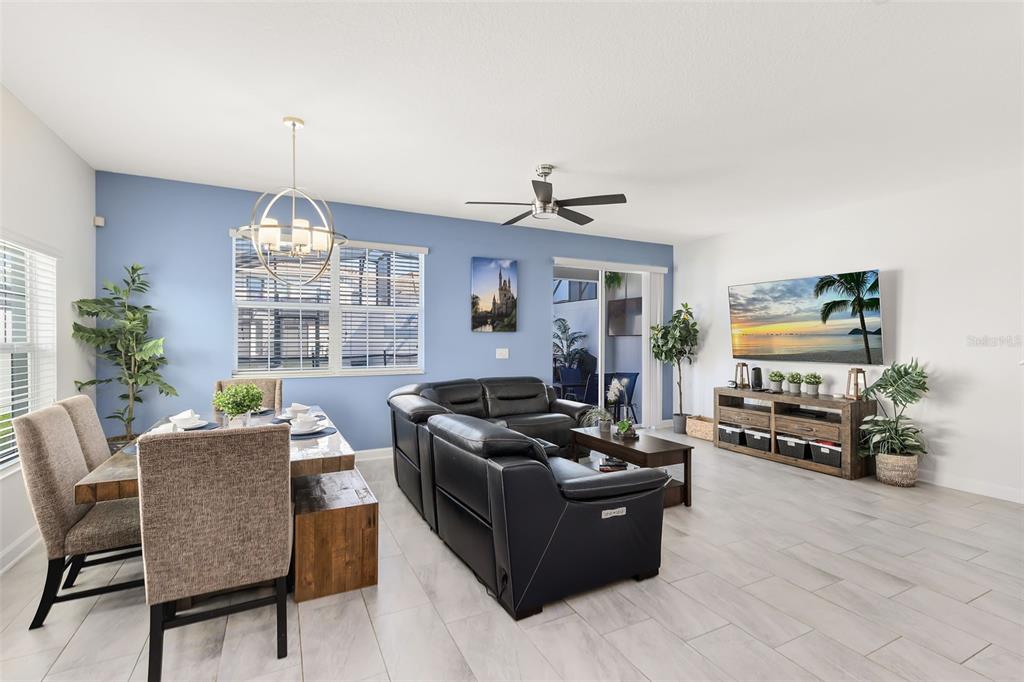 An open-concept living and dining area features a blue accent wall, black leather furniture, and tile flooring — 1575 SANDBAGGER DRIVE, DAVENPORT, FL