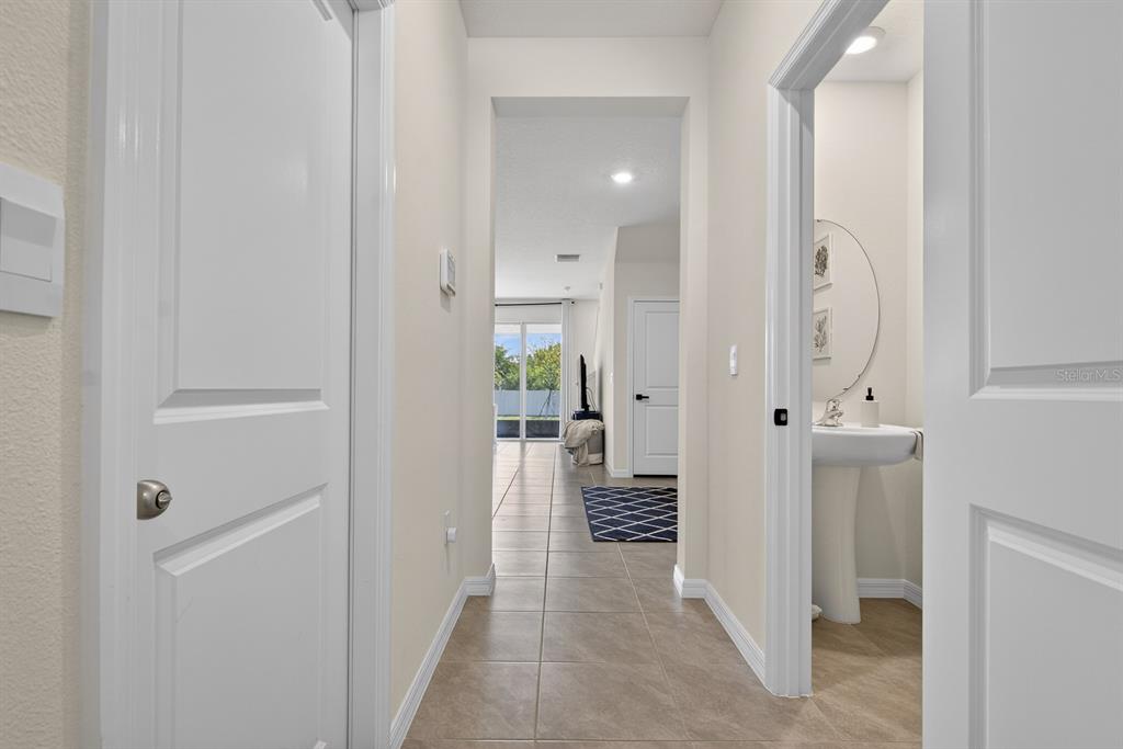 A hallway with tile flooring leads to a living area with a sliding glass door — 350 MANGROVE SHADE CIRCLE, APOLLO BEACH, FL