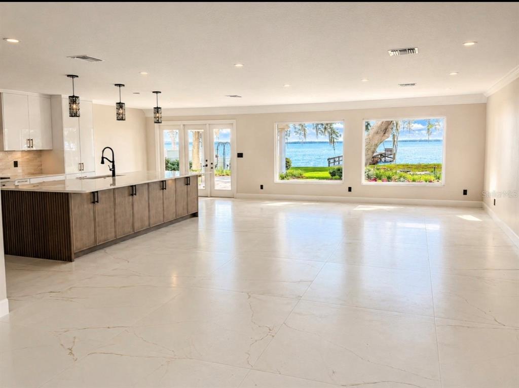 A modern kitchen with a large island overlooks a lake through expansive windows — 1341 W LAKESHORE DRIVE, CLERMONT, FL