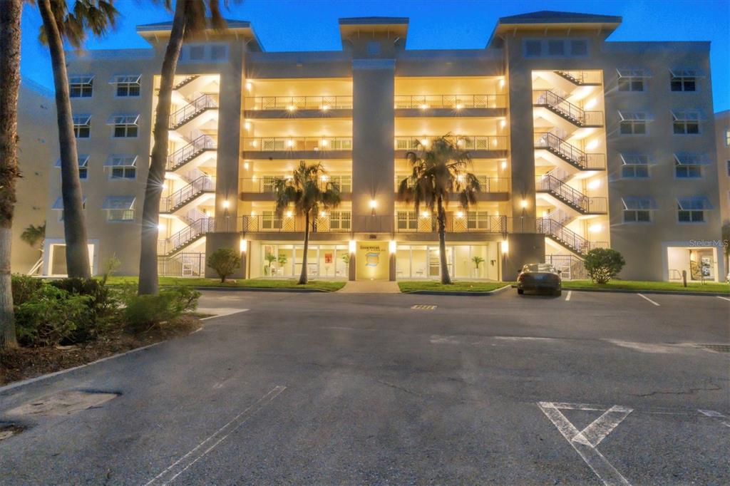 A multi-story apartment building with exterior staircases and a parking lot at dusk — 260 HIDDEN BAY DRIVE UNIT 402, OSPREY, FL