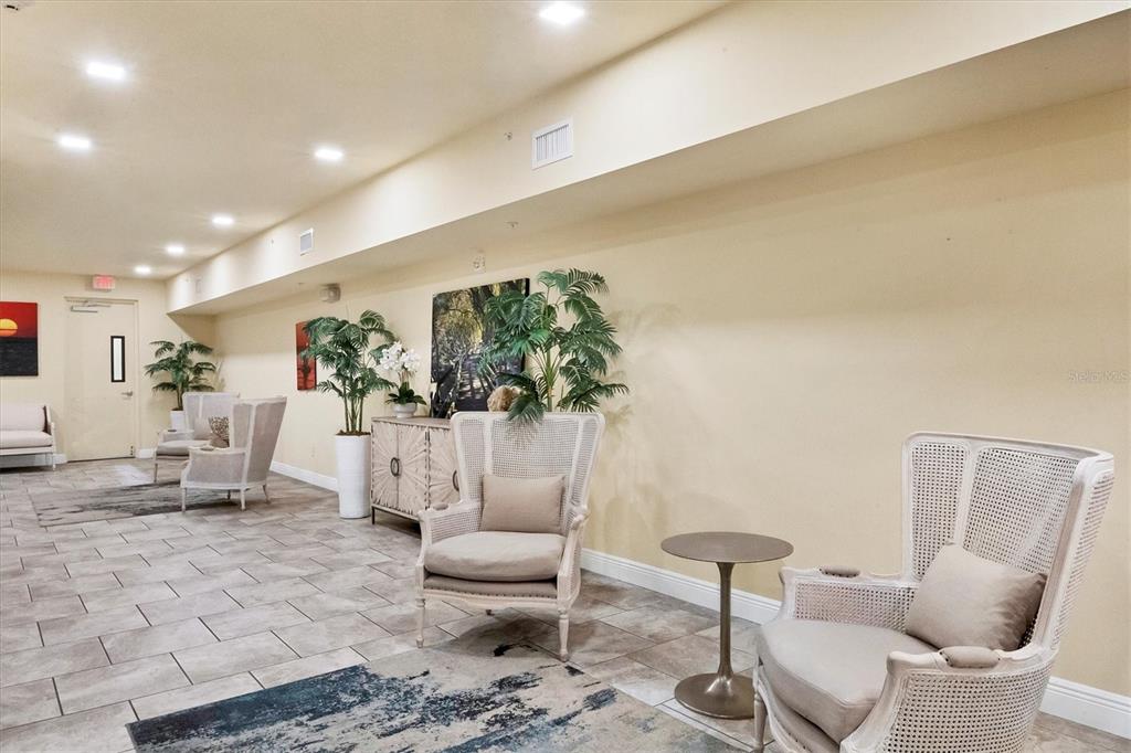 A lobby area features tile flooring, beige walls, several armchairs, and decorative potted plants — 260 HIDDEN BAY DRIVE UNIT 402, OSPREY, FL