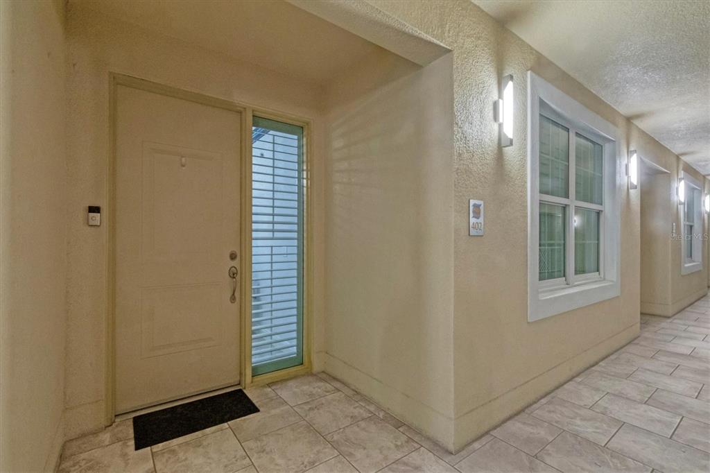 An exterior view of a residential building entrance featuring a door, window, and tiled floor — 260 HIDDEN BAY DRIVE UNIT 402, OSPREY, FL