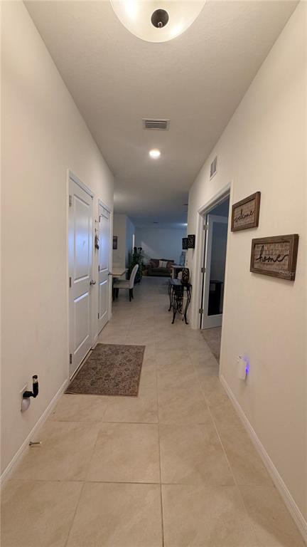A tiled hallway leads from the entryway toward an open living area with neutral walls — 6403 DEVESTA LOOP, PALMETTO, FL