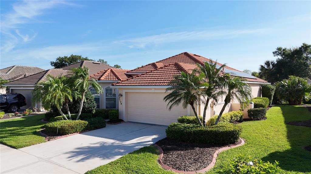 A single-story house with a tiled roof, a two-car garage, and palm trees in front — 5174 PINE SHADOW LANE, NORTH PORT, FL