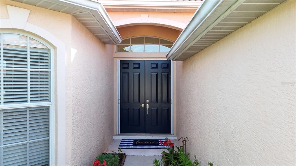 The exterior entrance features a dark double door with a transom window and side plants — 5174 PINE SHADOW LANE, NORTH PORT, FL