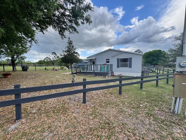 A single-story house with a front deck sits behind a dark wooden fence — 19231 NW HIGHWAY 335, WILLISTON, FL