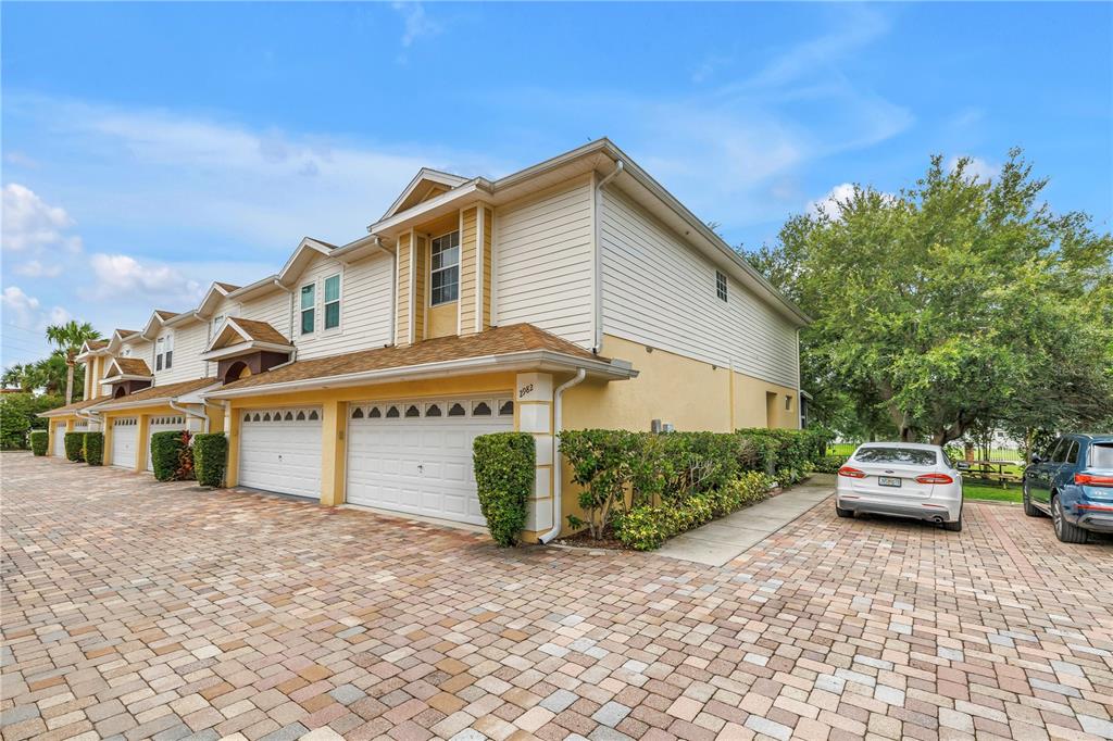 A screened-in porch features lime green chairs, a patterned rug, and a view of trees — 2982 ESTANCIA PLACE, CLEARWATER, FL