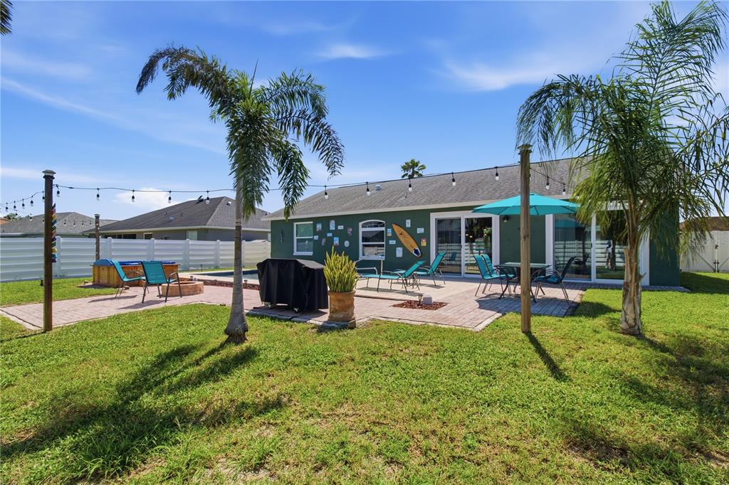 A backyard with a brick patio, swimming pool, palm trees, and string lights — 9301 71ST AVENUE E, PALMETTO, FL