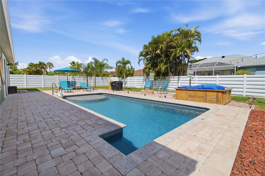 A backyard features a rectangular swimming pool, a wooden hot tub, and a paved patio — 9301 71ST AVENUE E, PALMETTO, FL