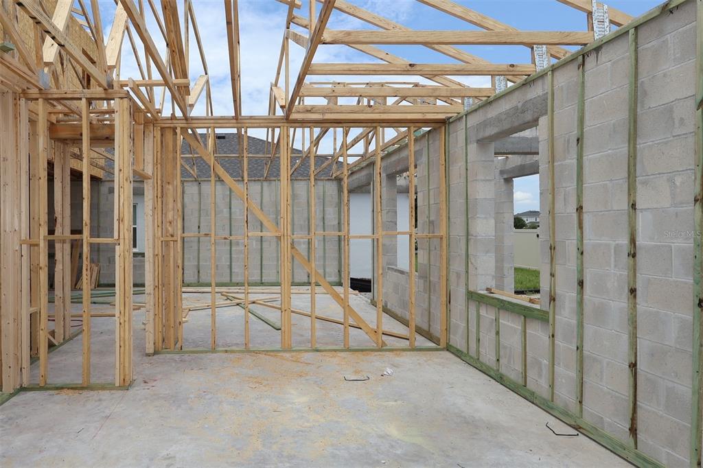 A construction site showing concrete block walls, wooden wall framing, and exposed roof trusses — 6777 YELLOW WARBLER BEND, ST CLOUD, FL