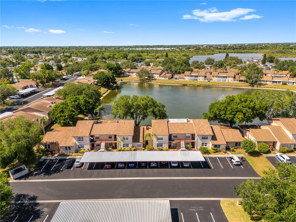 An aerial view shows a multi-story apartment complex with a parking carport and a lake — 3801 SAILMAKER LANE, HOLIDAY, FL