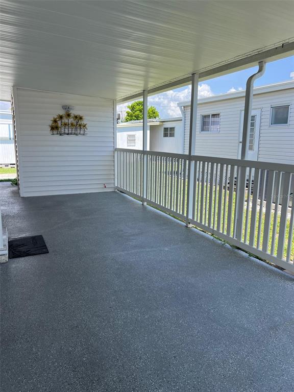 A covered outdoor patio with a concrete floor, white railing, and white siding — 36 THATCH PALM STREET E, LARGO, FL