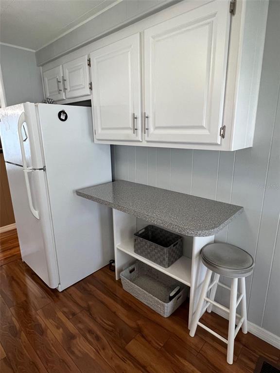 A white refrigerator sits next to a small kitchen counter with open shelving and a stool — 36 THATCH PALM STREET E, LARGO, FL
