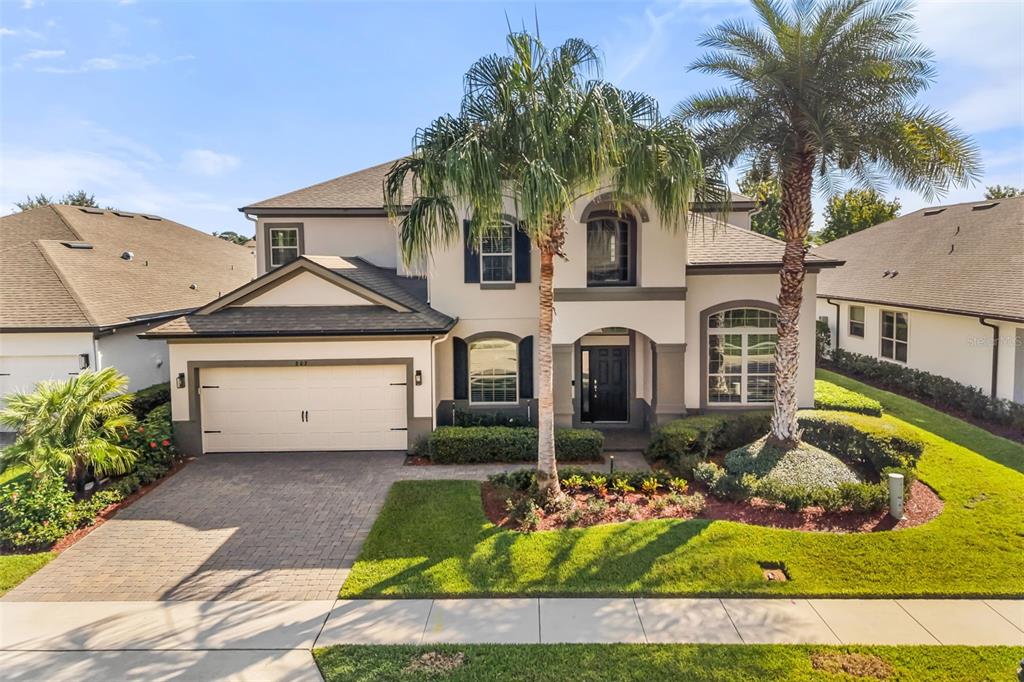A two-story suburban house with a beige stucco exterior, a two-car garage, and palm trees — 803 SHERBOURNE CIR, LAKE MARY, FL