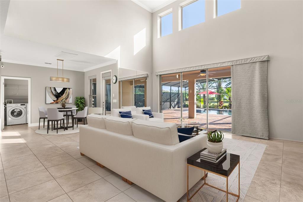 A bright, open-concept living and dining area features high ceilings, tile floors, and a pool view — 803 SHERBOURNE CIR, LAKE MARY, FL