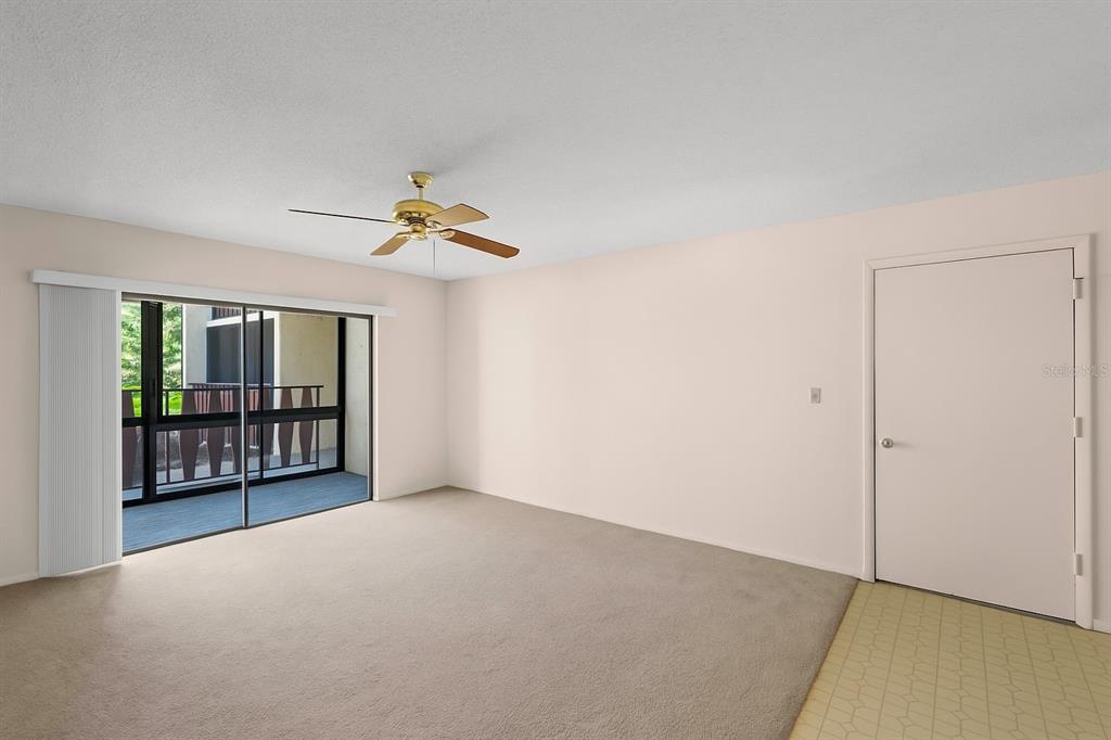 An empty room with beige carpet, a ceiling fan, and a sliding glass door to a balcony — 72 BOUNDARY BOULEVARD UNIT 226, ROTONDA WEST, FL