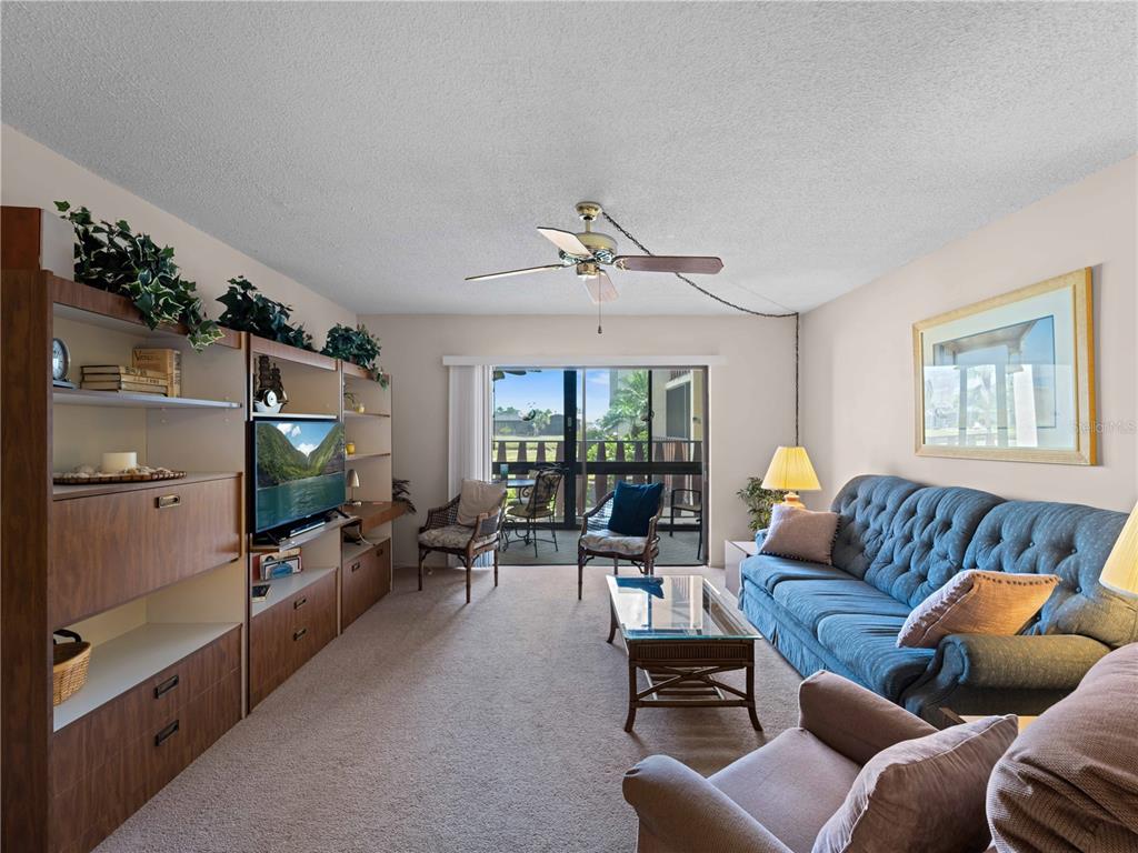 A living room features a blue sofa, a glass coffee table, and a large wall unit — 72 BOUNDARY BOULEVARD UNIT 226, ROTONDA WEST, FL