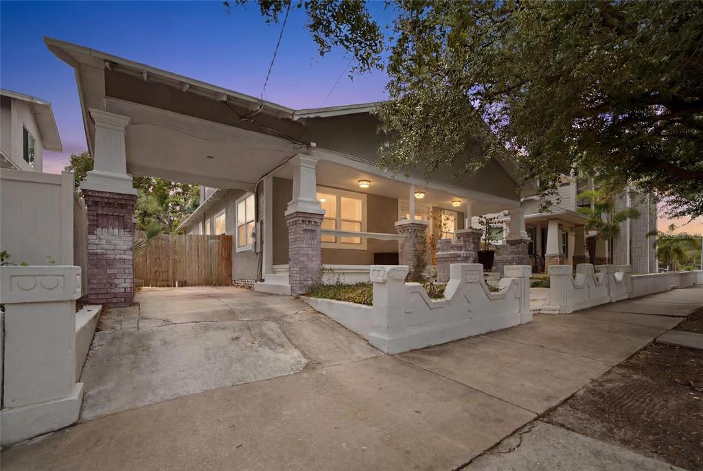 A covered front porch features a checkered tile floor, brick columns, and outdoor lighting — 2132 W BEACH STREET, TAMPA, FL