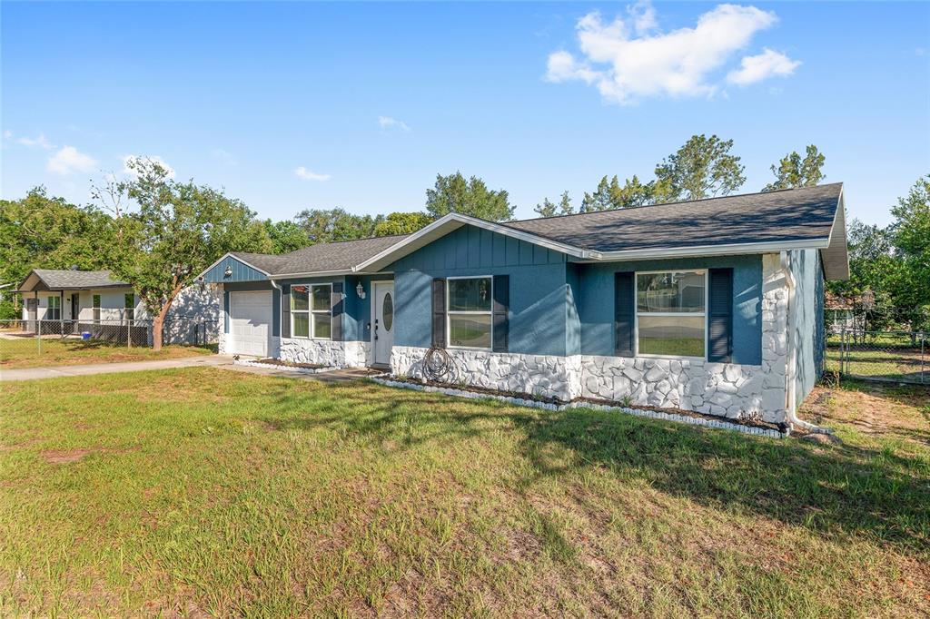 A blue single-story house features a white stone facade, a garage, and a front lawn — 69 SAPPHIRE ROAD, OCALA, FL