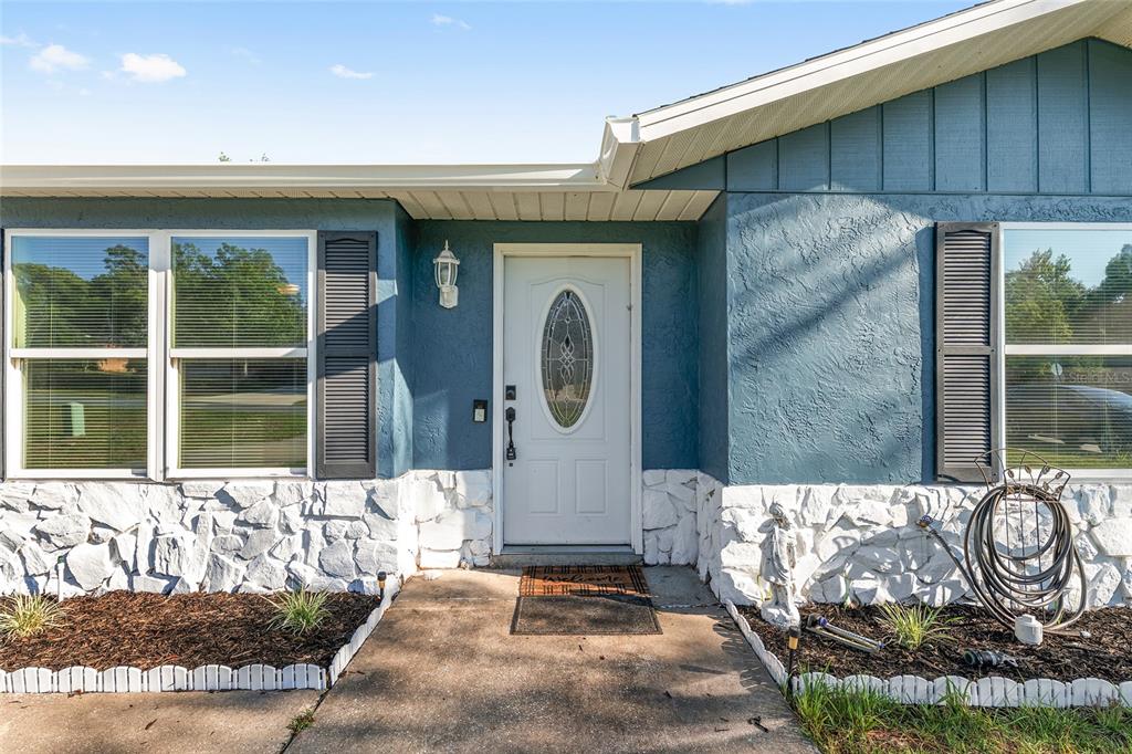 The exterior of a house features blue stucco walls, white stone accents, and a white door — 69 SAPPHIRE ROAD, OCALA, FL