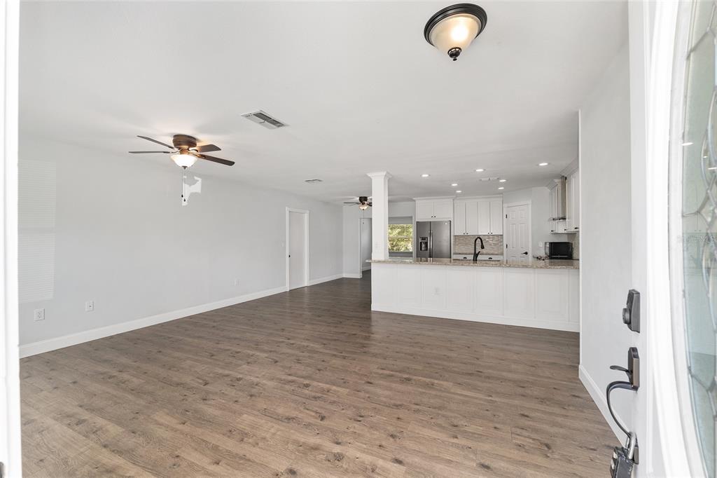 An open-concept living area features wood-look flooring, a kitchen island, and white cabinetry — 69 SAPPHIRE ROAD, OCALA, FL