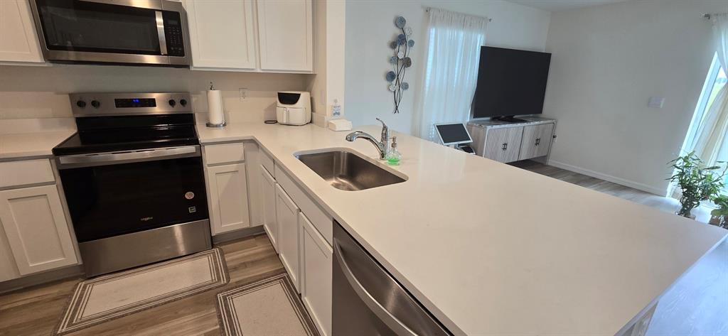 A kitchen with white cabinets, stainless steel appliances, and a quartz countertop island — 8375 GOWER TRAIL, WILDWOOD, FL