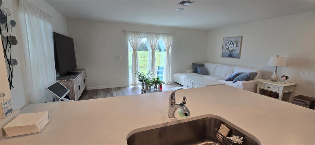 A kitchen island overlooks a living room with a white sectional sofa and sliding doors — 8375 GOWER TRAIL, WILDWOOD, FL