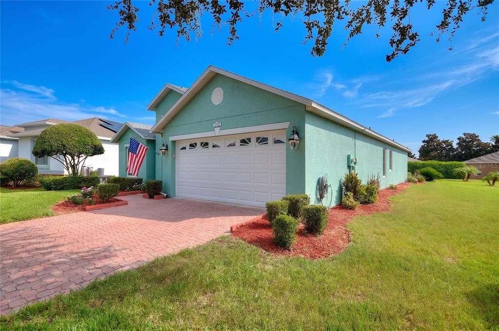 A light green house with a white garage door and a brick paver driveway — 4132 MARTINDALE LOOP, WINTER HAVEN, FL