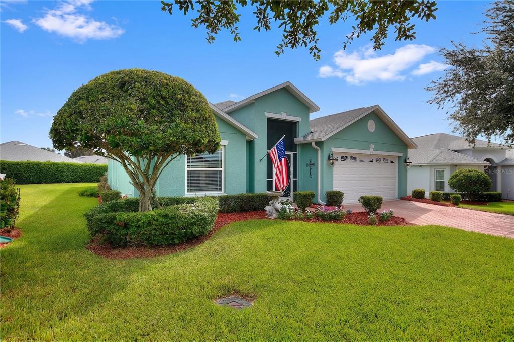 A teal single-story house with a white garage and a manicured lawn under a blue sky — 4132 MARTINDALE LOOP, WINTER HAVEN, FL