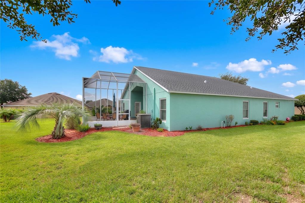 The exterior of a light green house with a screened-in patio and a grassy yard — 4132 MARTINDALE LOOP, WINTER HAVEN, FL