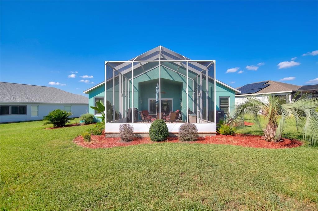 The exterior of a teal house features a screened-in patio and a landscaped yard — 4132 MARTINDALE LOOP, WINTER HAVEN, FL
