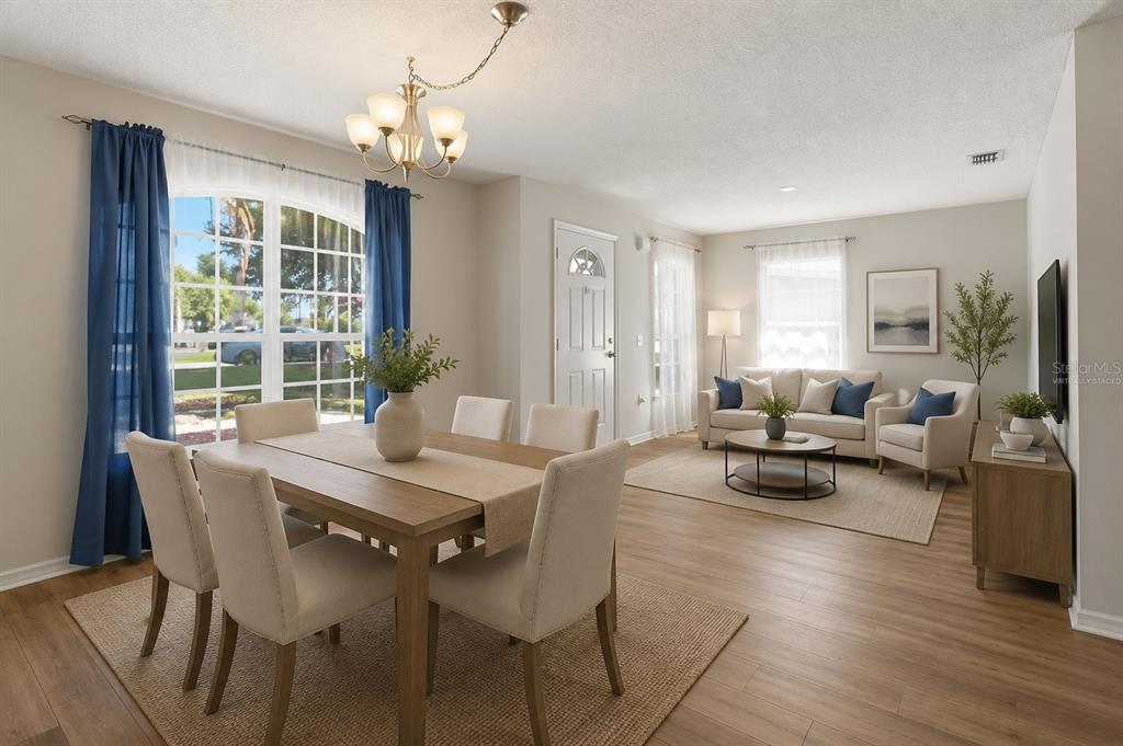 A dining area with a wooden table and chairs opens into a living room — 372 LAKE DAISY CIR, WINTER HAVEN, FL