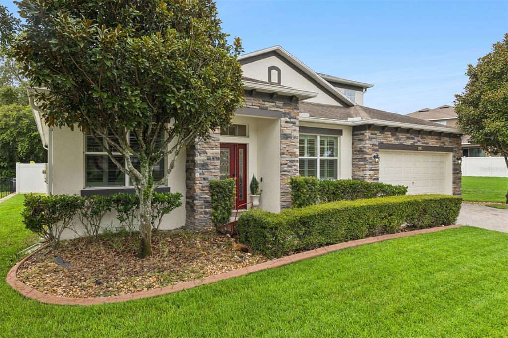 A single-story house with a stone facade, red front door, and a two-car garage — 2205 PICKFORD CIRCLE, APOPKA, FL