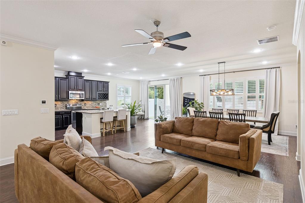 An open-concept living room, dining area, and kitchen with dark cabinets and brown sofas — 2205 PICKFORD CIRCLE, APOPKA, FL