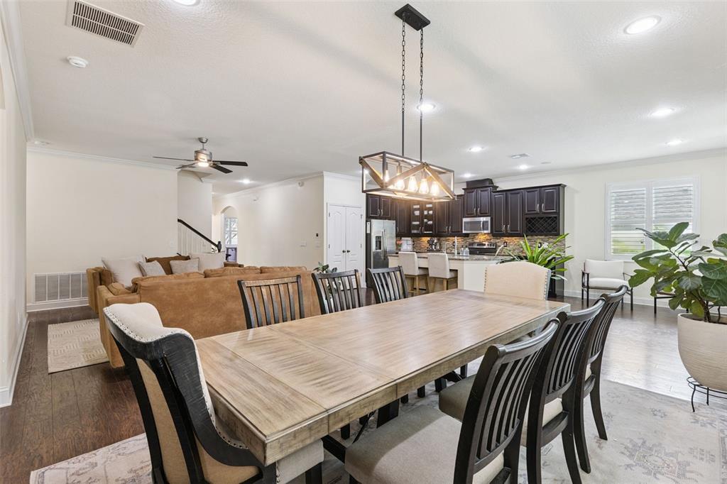 An open-concept dining room features a wooden table, dark chairs, and a view of the kitchen — 2205 PICKFORD CIRCLE, APOPKA, FL