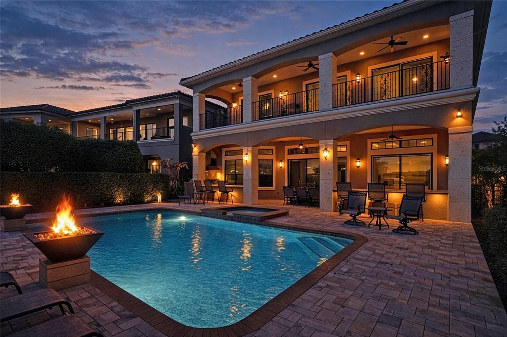 A two-story house with a pool, fire pit, and covered patio at twilight — 451 MUIRFIELD LOOP, REUNION, FL