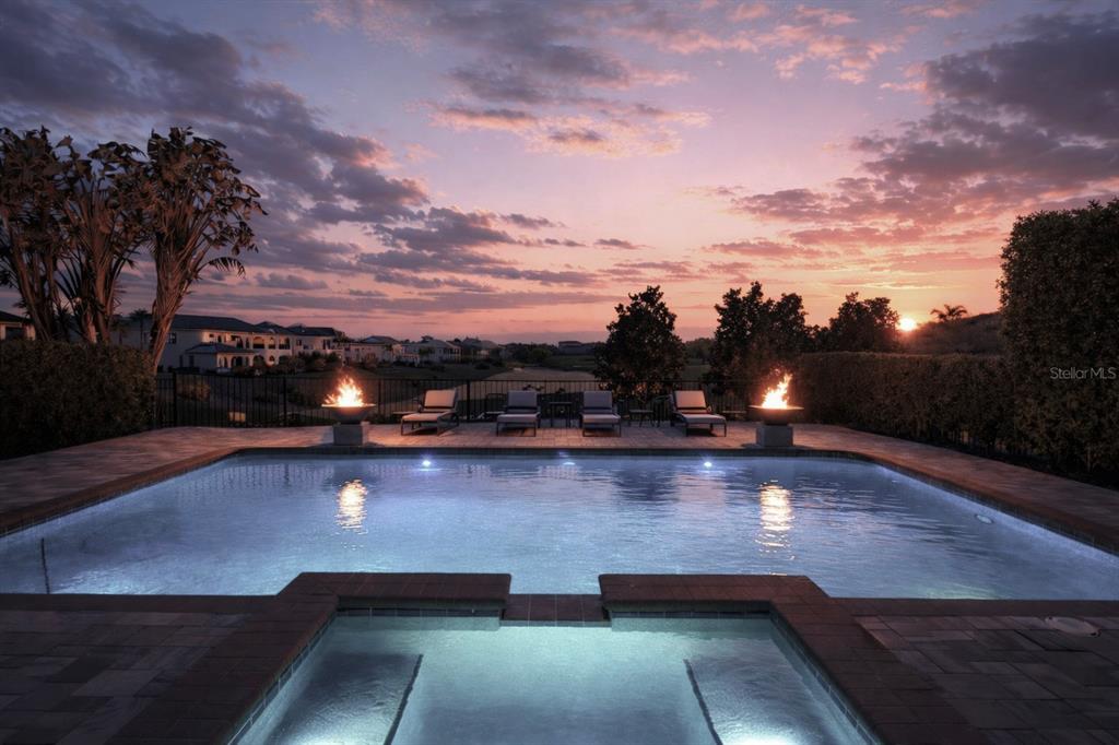 A swimming pool and hot tub at sunset with fire bowls and lounge chairs — 451 MUIRFIELD LOOP, REUNION, FL