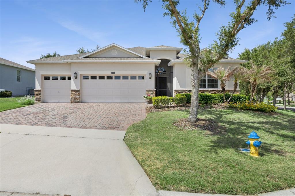A single-story house with a three-car garage, stone accents, and a paved driveway — 2892 SANDY CAY STREET, CLERMONT, FL