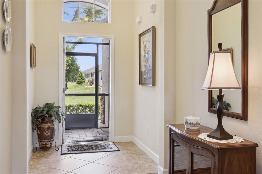 A bright entryway features tile flooring, a screen door, a console table, and a mirror — 2892 SANDY CAY STREET, CLERMONT, FL