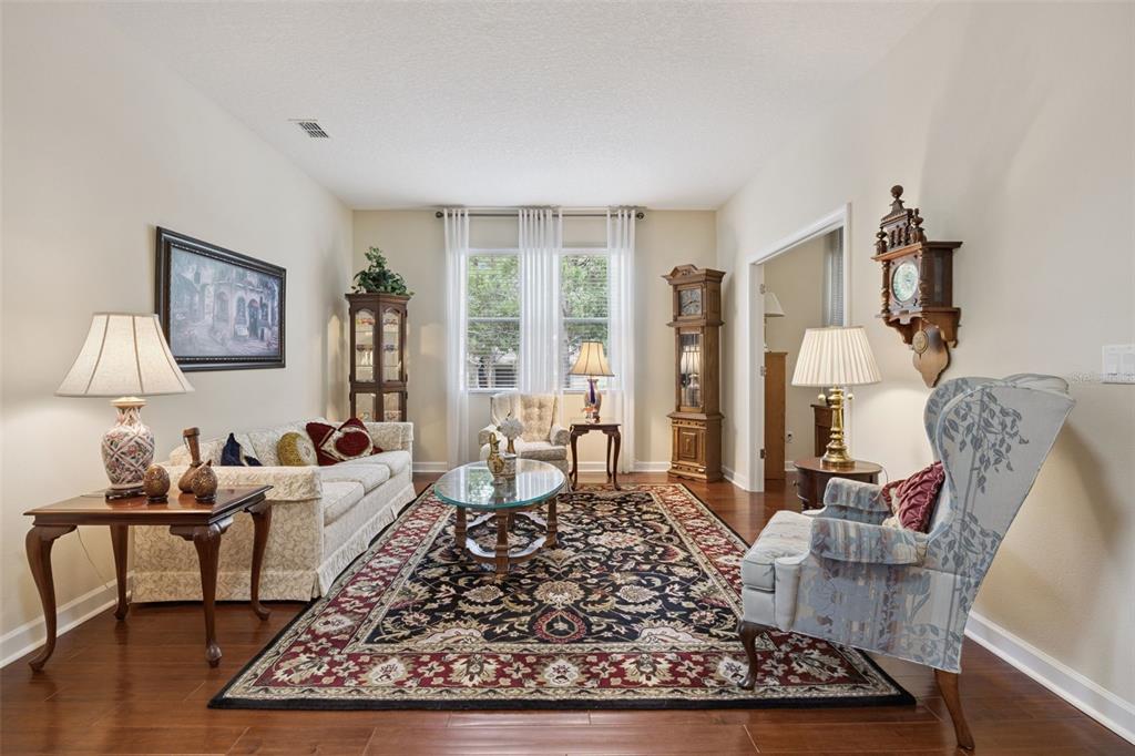 A formal living room features hardwood floors, a large patterned area rug, and traditional furniture — 2892 SANDY CAY STREET, CLERMONT, FL