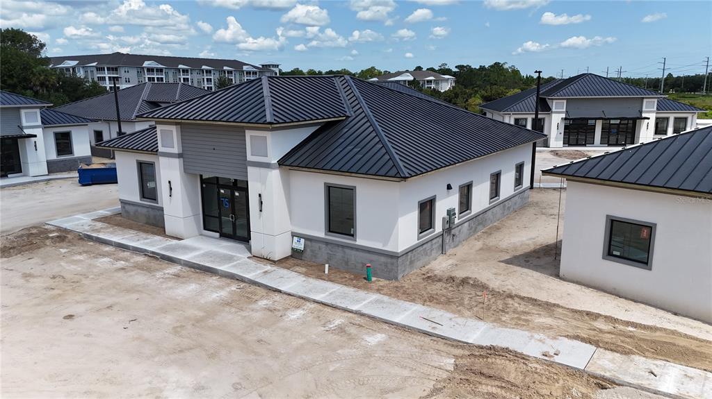 An aerial view shows a construction site with a concrete block building frame and nearby houses — 75 EXCHANGE LOOP LOOP UNIT 8, PALM COAST, FL
