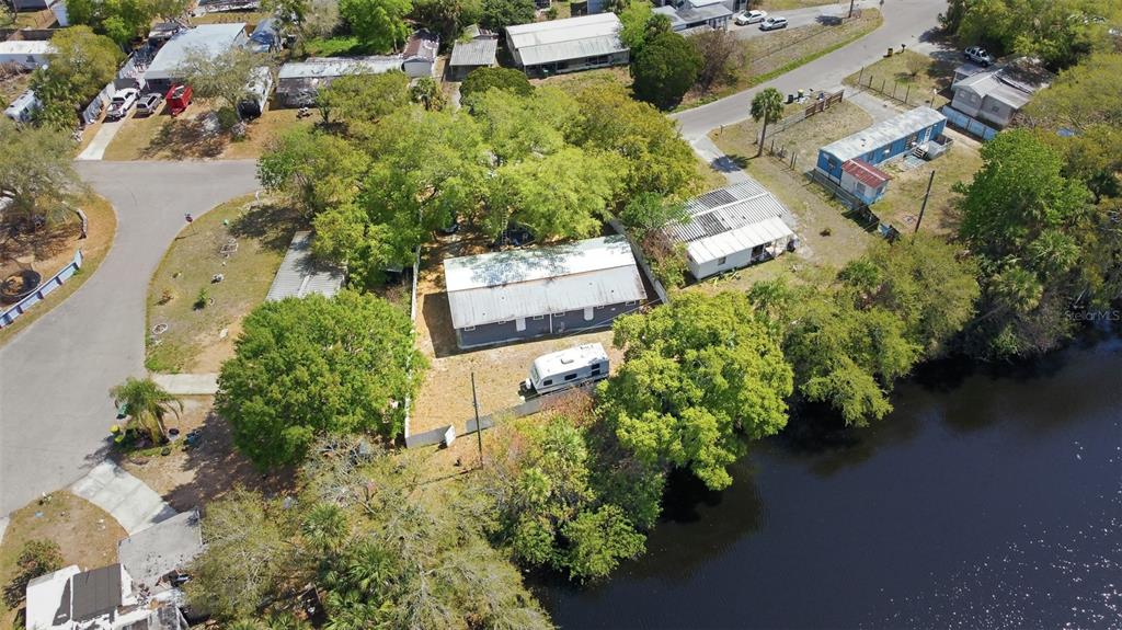 An aerial view shows a house with a metal roof, a camper, and waterfront access — 6991 ASH DRIVE, COCOA, FL