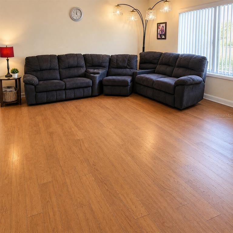 A living room features a large gray sectional sofa, wood-look flooring, and a floor lamp — 1715 9TH AVENUE, DELAND, FL