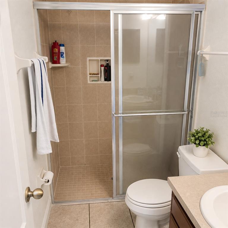A bathroom features a tiled walk-in shower with sliding glass doors and a toilet — 1715 9TH AVENUE, DELAND, FL