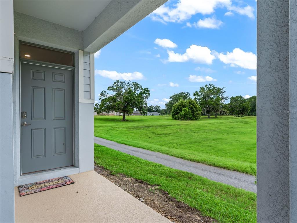 A view from a covered entryway looking out onto a grassy field and a path — 5478 NW 46TH LANE RD, OCALA, FL