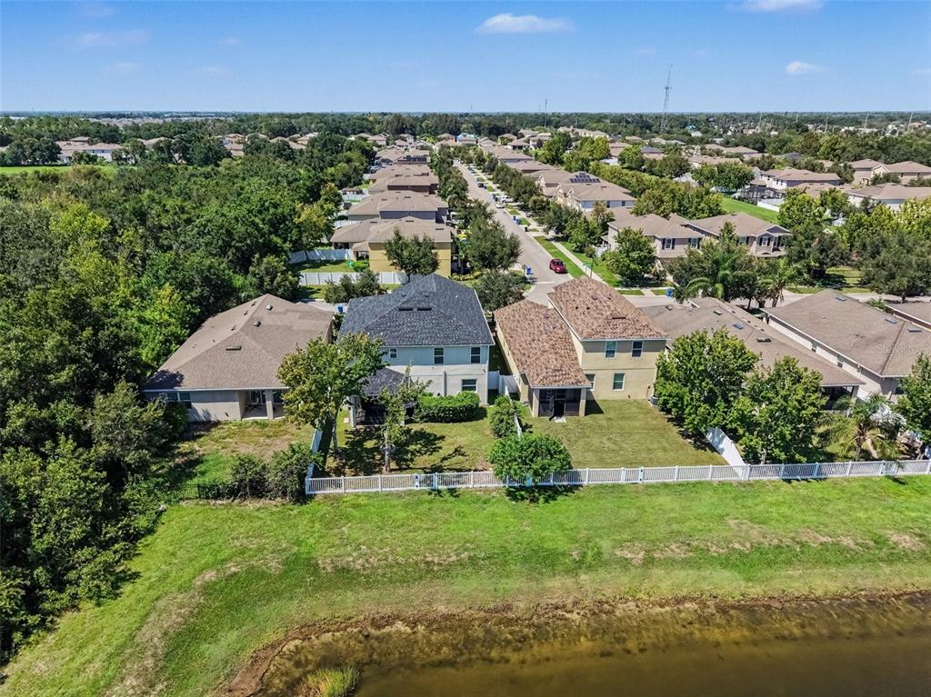 An aerial view shows suburban houses with backyards bordering a pond and wooded area — 10413 AVIAN FORREST DRIVE, RIVERVIEW, FL