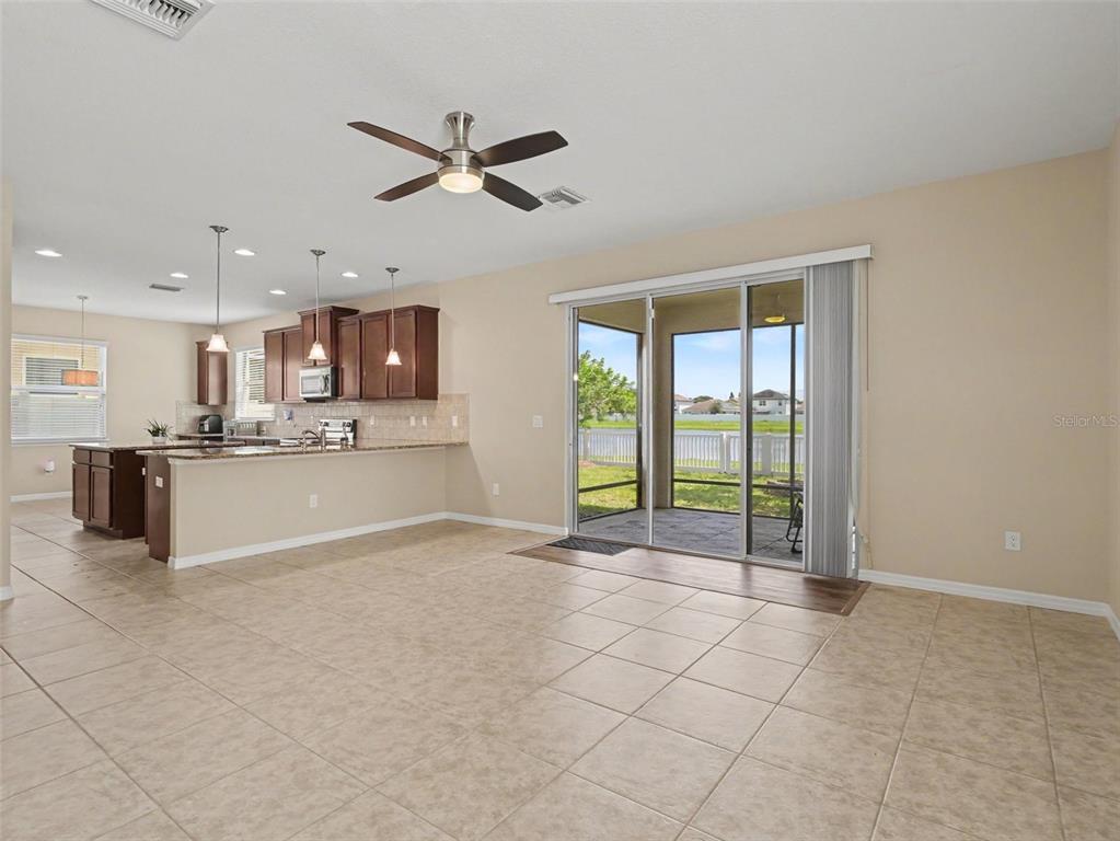 An open-concept kitchen and living area with tile floors, a ceiling fan, and sliding glass doors — 10413 AVIAN FORREST DRIVE, RIVERVIEW, FL