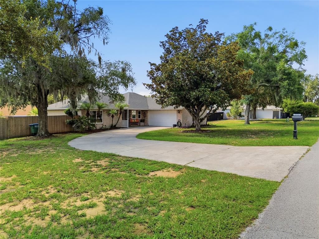 A single-story brick house with a large front tree and a grassy yard — 17522 HILLSIDE DRIVE, MONTVERDE, FL